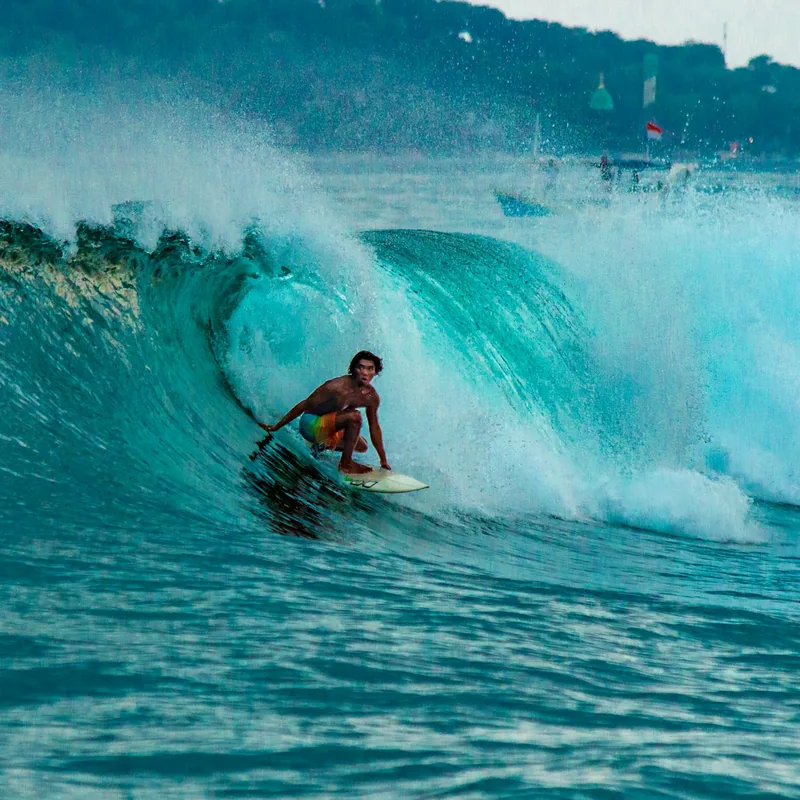 Surfer riding the face of a turquoise tropical wave